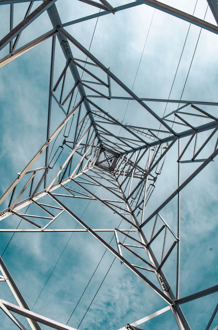 View from inside a metal transmission tower against a blue sky.
